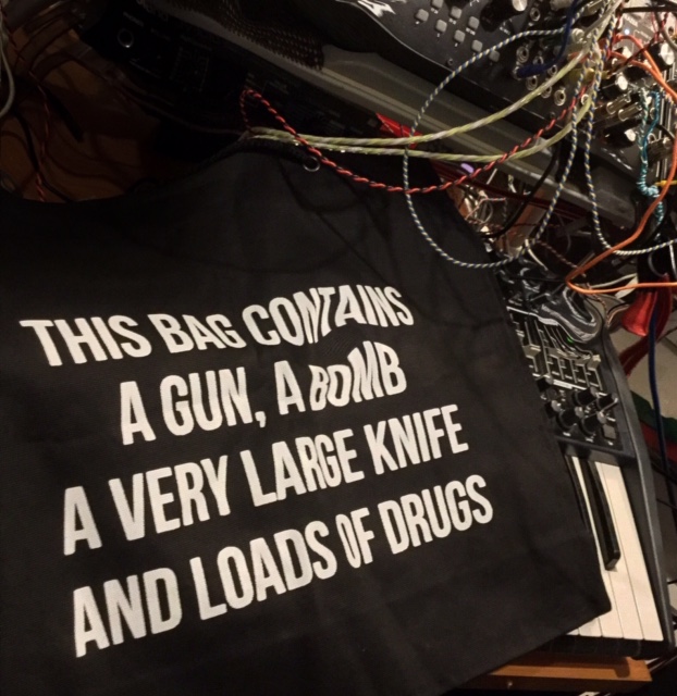 black bag with  bold white text reads, 'this bag contains a gun, a bomb, a very large knife and a great big quantity of go fORK yourself'